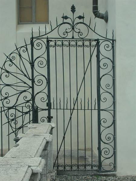 Green wrought iron gate and railing against a white wall