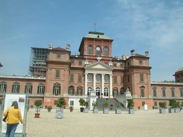 Woman in yellow before Racconigi Castle, brick facade with clock