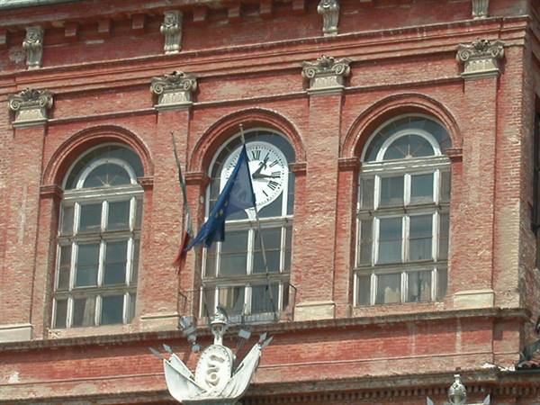 Clock and flags on red brick facade with arched windows