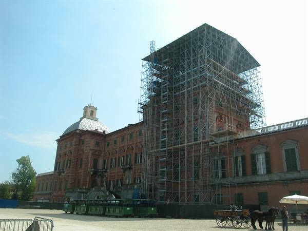 Racconigi Royal Palace under scaffolding, horse carriage passing nearby