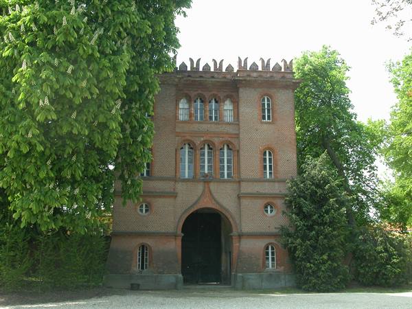 Brick gatehouse with crenellations and arched entrance among trees