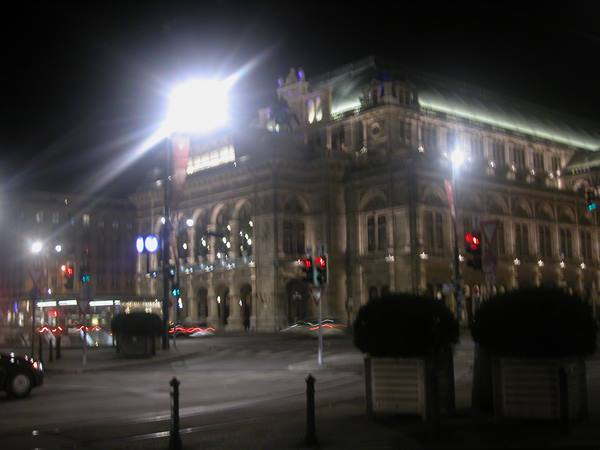 Vienna State Opera lit at night, blurred traffic in front of the stone facade