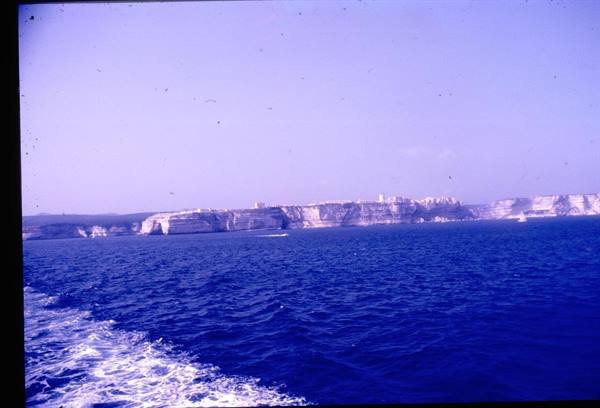 White limestone cliffs of Bonifacio seen from the sea, boat wake in foreground