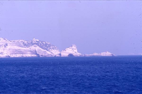 White limestone cliffs rising from blue sea, lighthouse on top