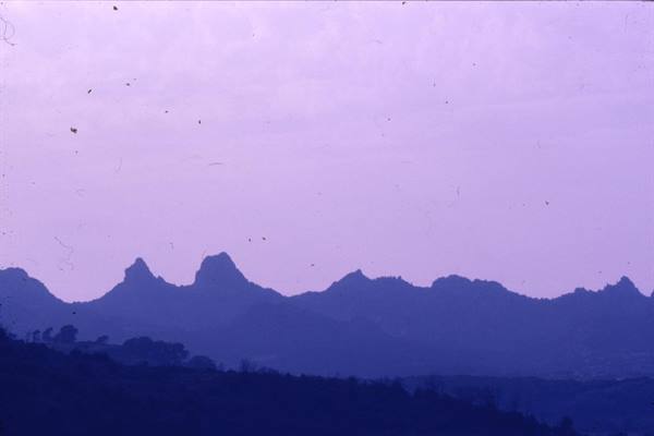 Purple mountain ridges silhouetted under a pale snowy sky