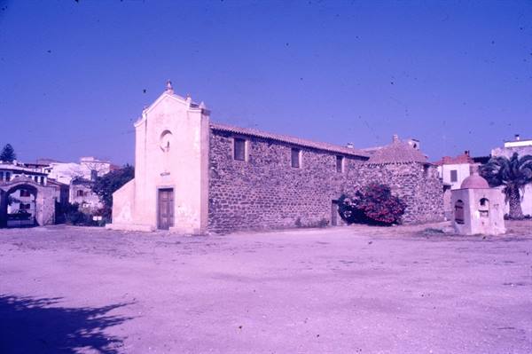 Stone church with plastered facade on sandy square, blue sky
