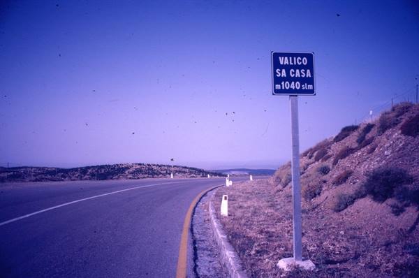 Blue sign Valico Sa Casa 1040 meters on asphalt road among dry hills