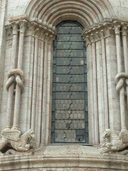 Modena Romanesque apse: knotted columns, stone griffins and narrow window