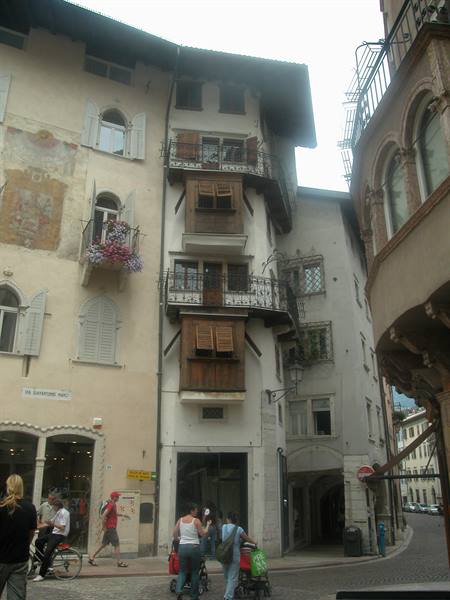 Medieval stone and wooden houses in Innsbruck, pedestrians and bicycles under grey sky
