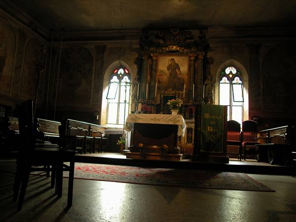 Church interior with altar, wall paintings, open windows and empty chairs
