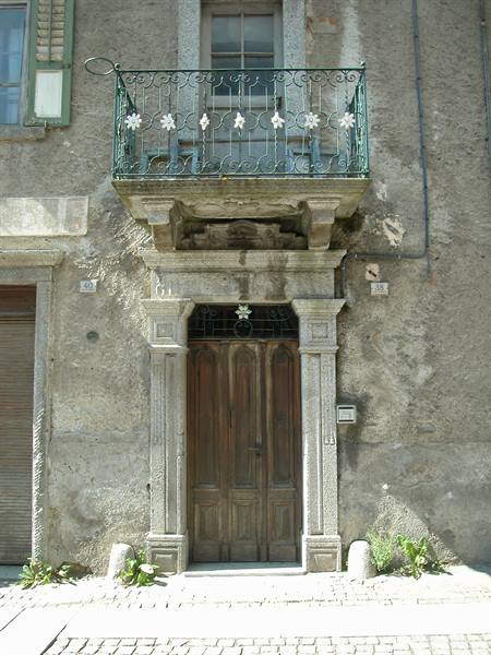Wooden door with green wrought iron balcony on stone facade