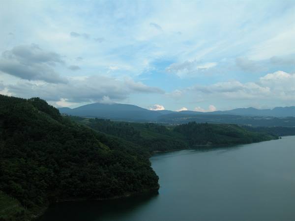 Lake surrounded by forested hills under a cloudy sky
