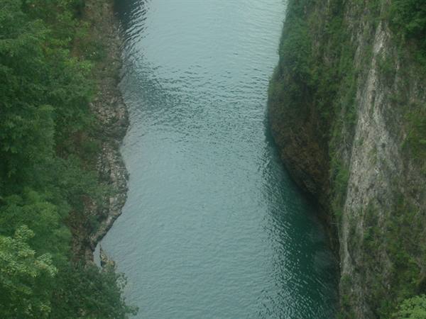 Emerald river flowing between steep rock walls covered in greenery