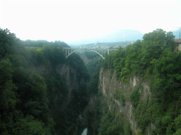 arch bridge spanning a rocky gorge with river and trees