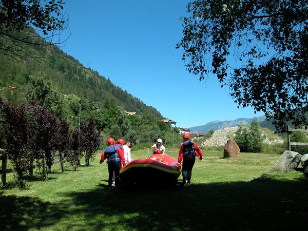 Group in red helmets carrying an inflatable raft across the grass