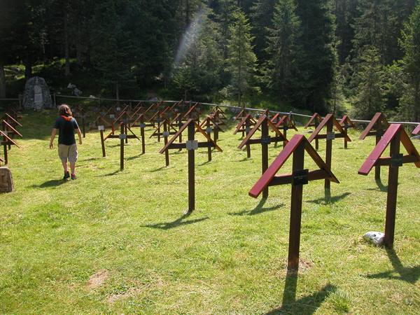 Child walks among wooden red crosses of the military cemetery