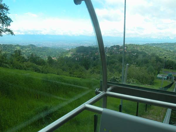 Through Superga funicular curved glass, green hills and Turin in the distance
