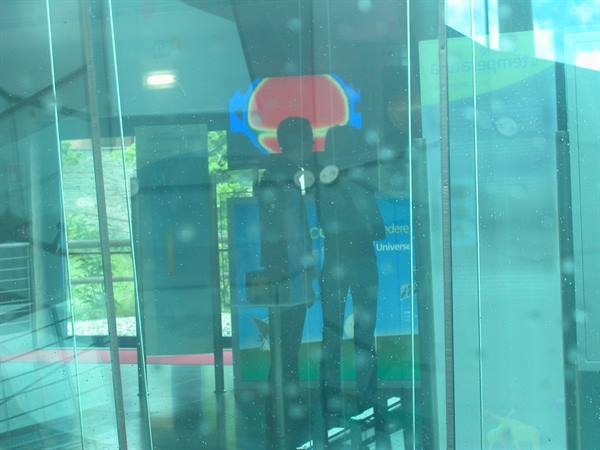 Two visitors reflected behind glass in a museum with exhibit panels