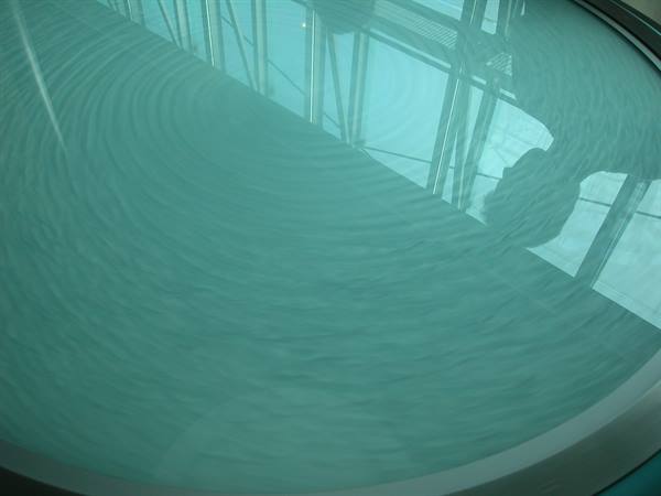 Circular pool with turquoise water reflecting the glass structure above