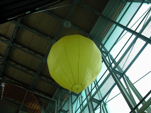 Yellow balloon hanging beneath a wooden and glass building roof
