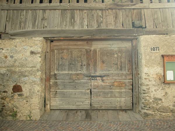 Old wooden door on stone wall with date 1877