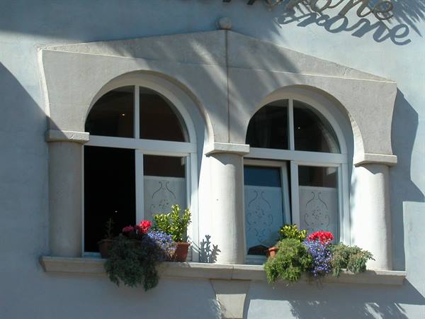 Stone mullioned window with two arched windows and flowers on sills