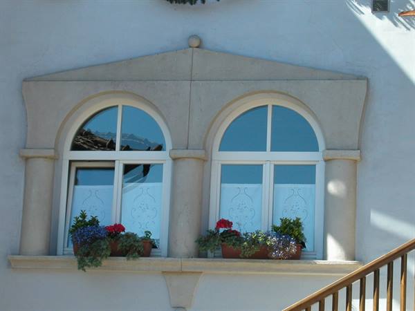 Double arched window with flower boxes on a white plastered facade