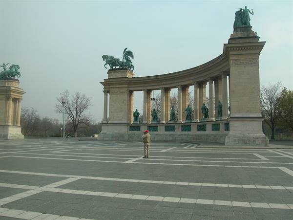 Heroes' Square in Budapest: stone colonnade with bronze statues, man walking