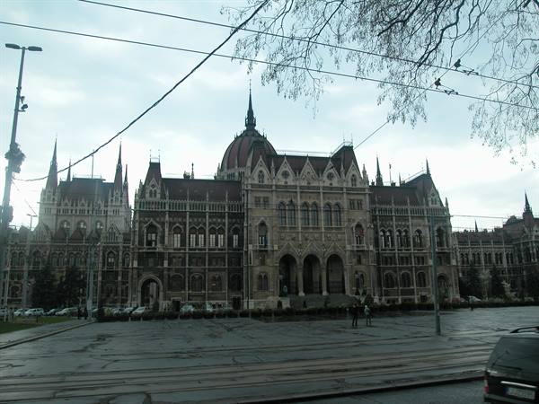 Budapest Parliament under a grey sky, tram wire in the foreground