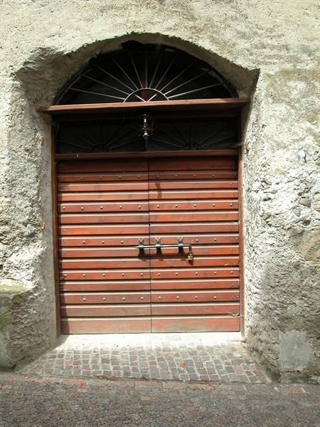 Red wooden door locked with bolt, stone arch and iron fanlight