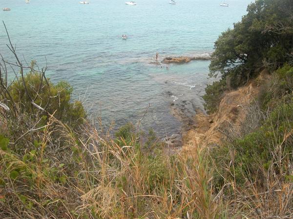 Turquoise bay with rocks, moored boats and a swimmer on a rock