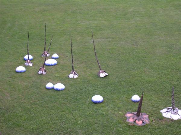 Mushroom-shaped sculptures with long stalks on green lawn