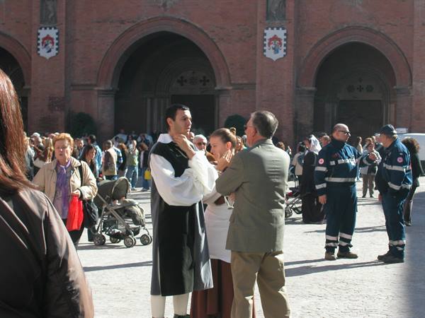 Actors in medieval costume in front of the brick facade of Palazzo Re Enzo, Bologna