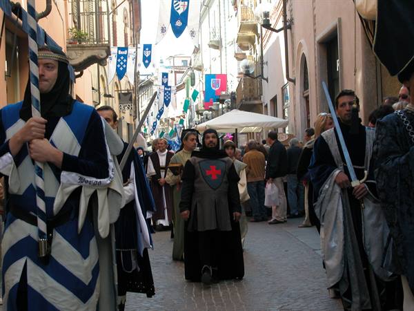 Medieval parade through an Italian alley, men in costumes with swords and banners