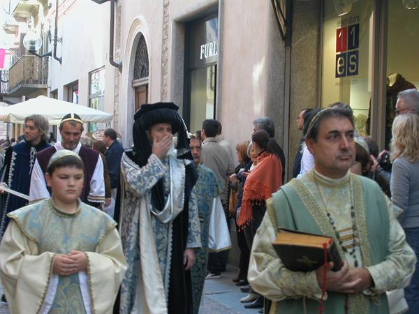 Medieval costume parade through the street, man in gold crown holding a book