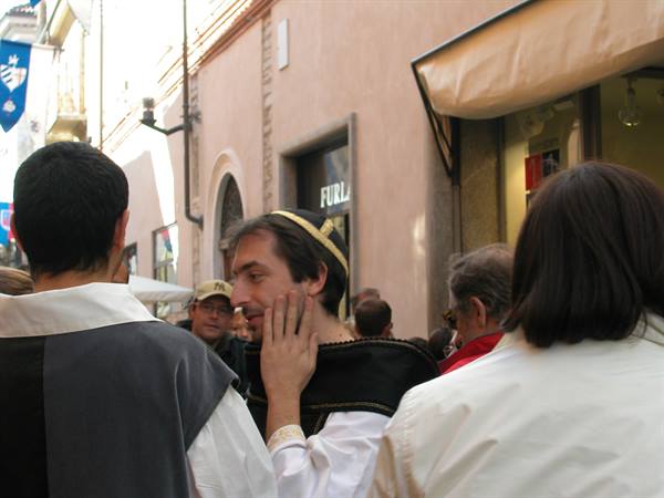 Men in medieval costumes walking among the crowd, banners hanging above