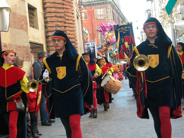Medieval parade of trumpeters in blue and red costumes through Alba's streets