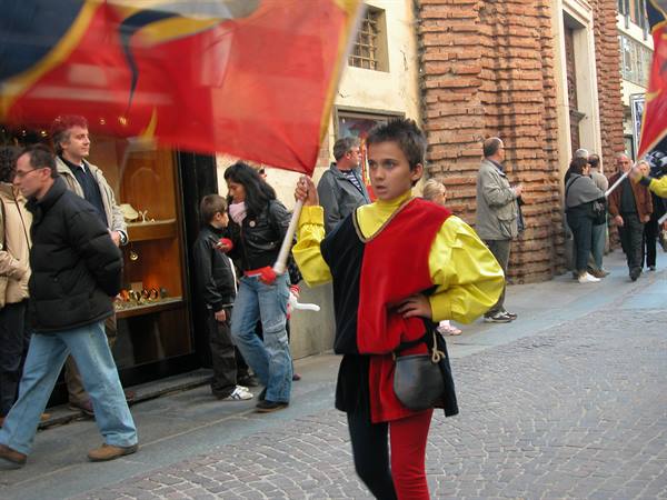 Young flag waver in red and yellow costume waves a banner in Florence