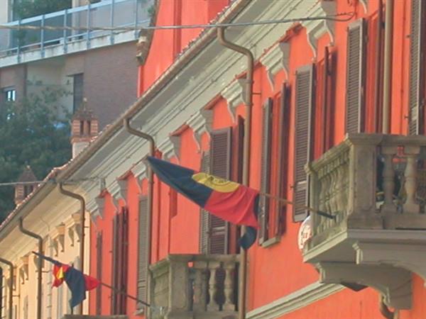 Orange building with shutters and stone balconies, red and black flags waving