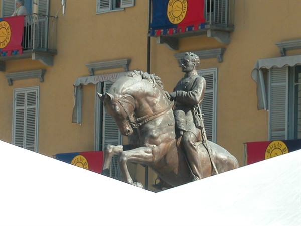 Bronze equestrian statue before an ochre building with banners hanging from balconies