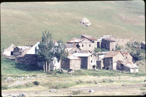 Village of stone houses with rusty roofs beneath a green hillside