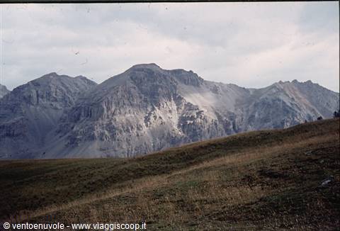 Rocky mountains under cloudy sky above an alpine meadow