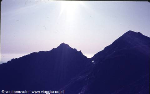 Two rocky peaks backlit under the high sun