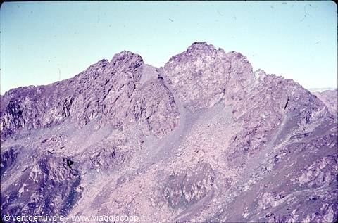 Grey rocky peaks against blue sky, with scree slopes and mineral ridges