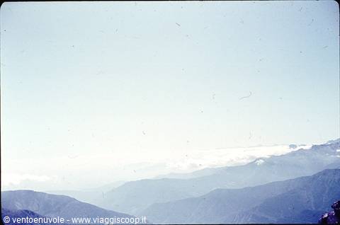 Blue mountain ridges rising above clouds under a hazy sky