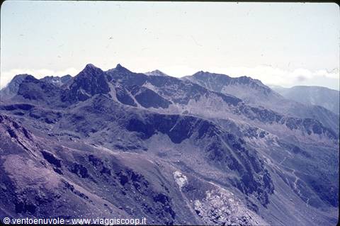 Rocky mountain peaks under clear sky, grassy slopes and scree