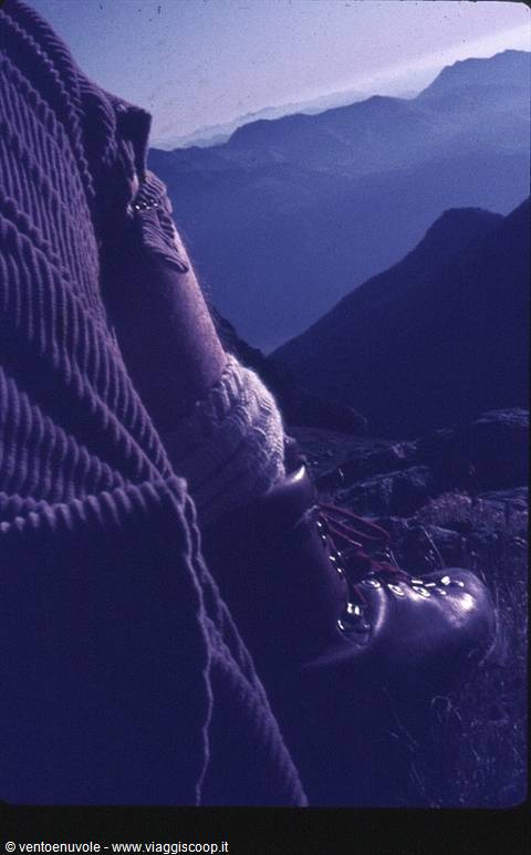 Hiking boot and wool sweater above rocky ridges at dusk