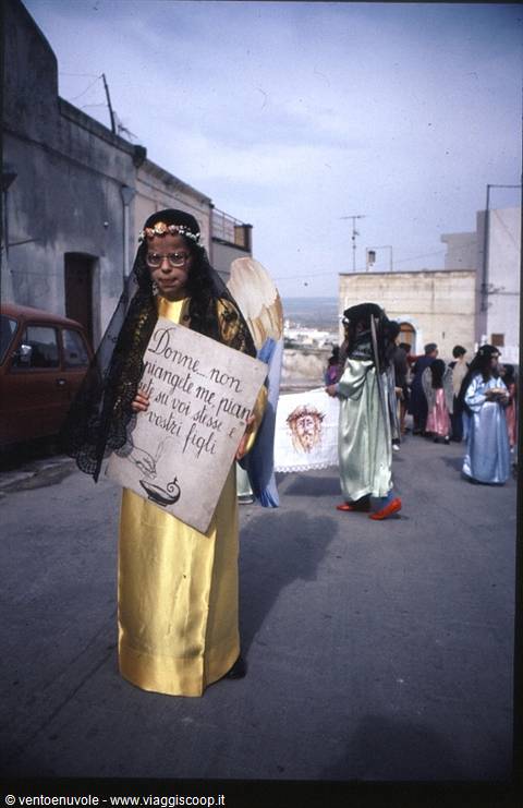 Girl in golden costume holding a sign during Easter street procession