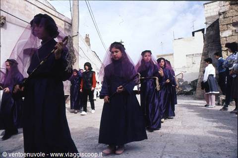 Veiled girls in purple robes parade with crowns of thorns through Matera's alleys