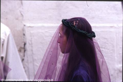 Girl with green crown and purple veil in front of white wall